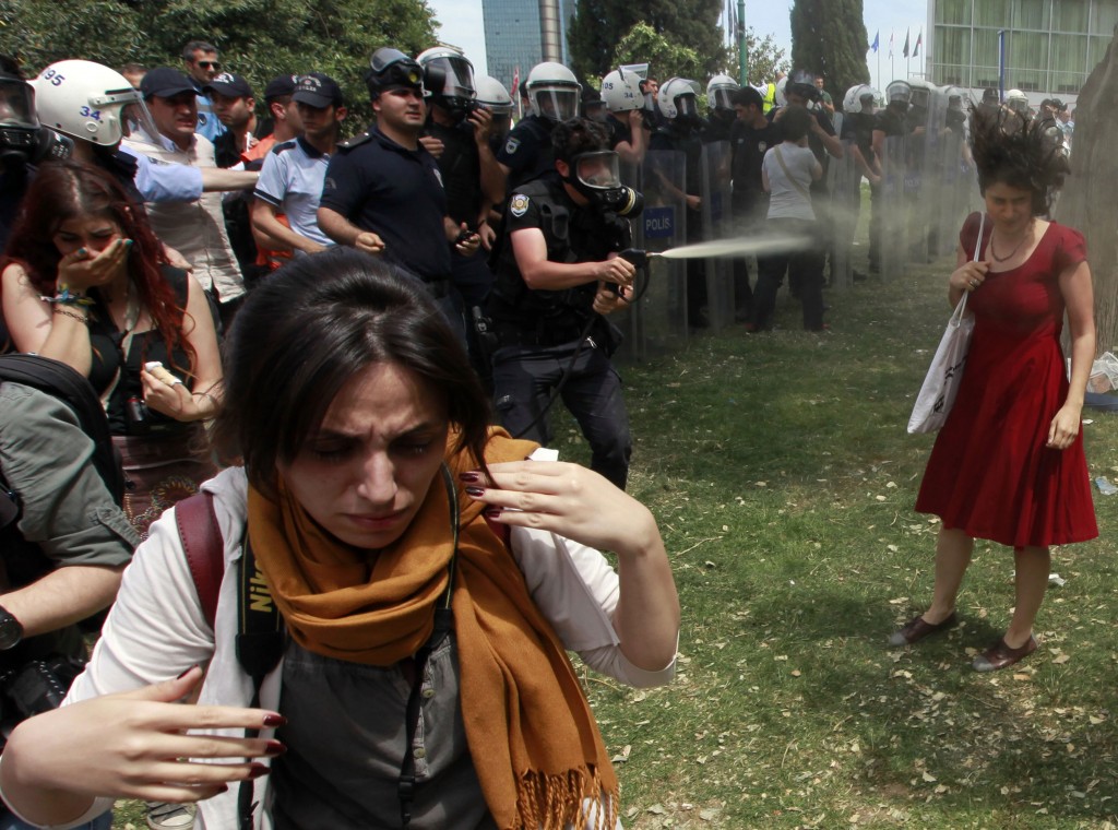 A Turkish riot policeman uses tear gas as people protest against the destruction of trees in a park brought about by a pedestrian project, in Taksim Square in central Istanbul 28 May 2013. REUTERS / Osman Orsal